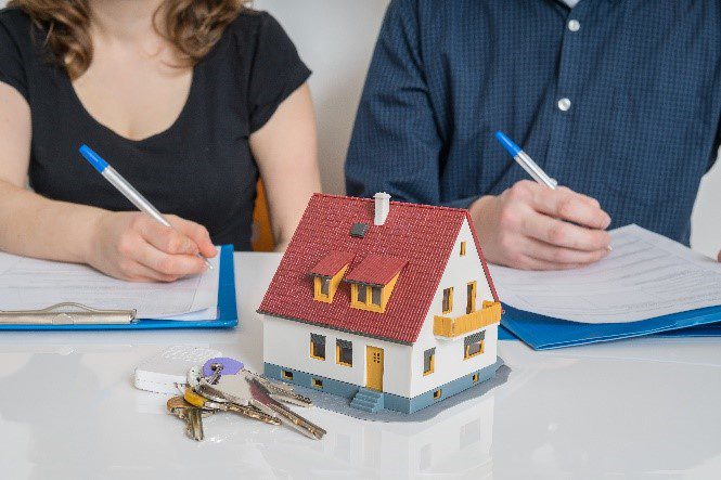 Two people signing paperwork to become tenants in common on home purchase