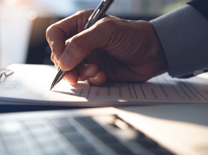 Businessman, executive manager hand filling paper business document, signing contract, partnership agreement and working on laptop computer on desk in modern office, close up