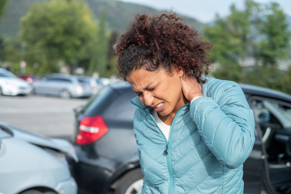 A woman rubbing her neck after a car accident.
