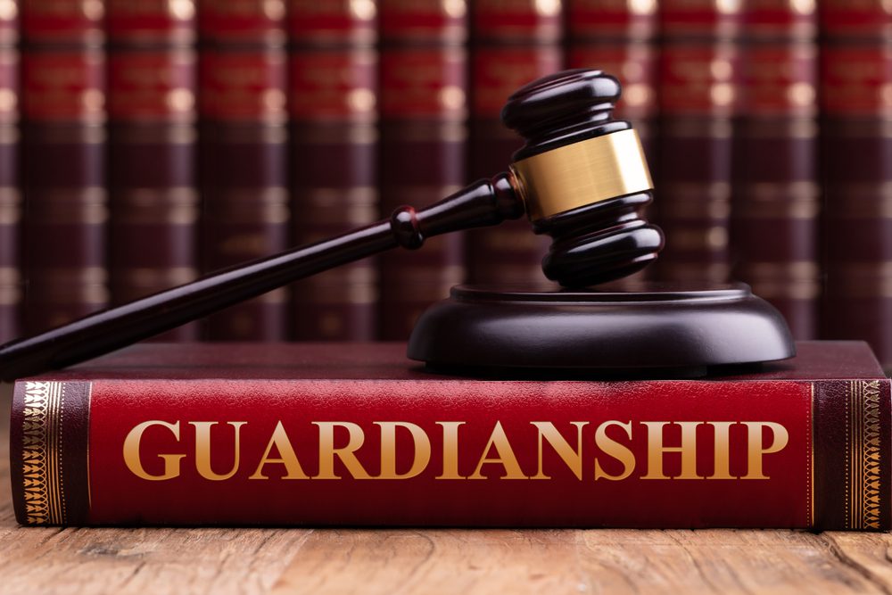 Gavel and striking block on law book with "Guardianship" title on wooden desk