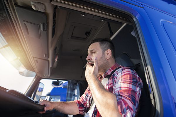 A truck driver yawns at the wheel of the vehicle