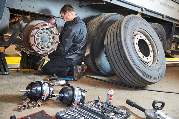 A mechanic works on the brakes of a truck