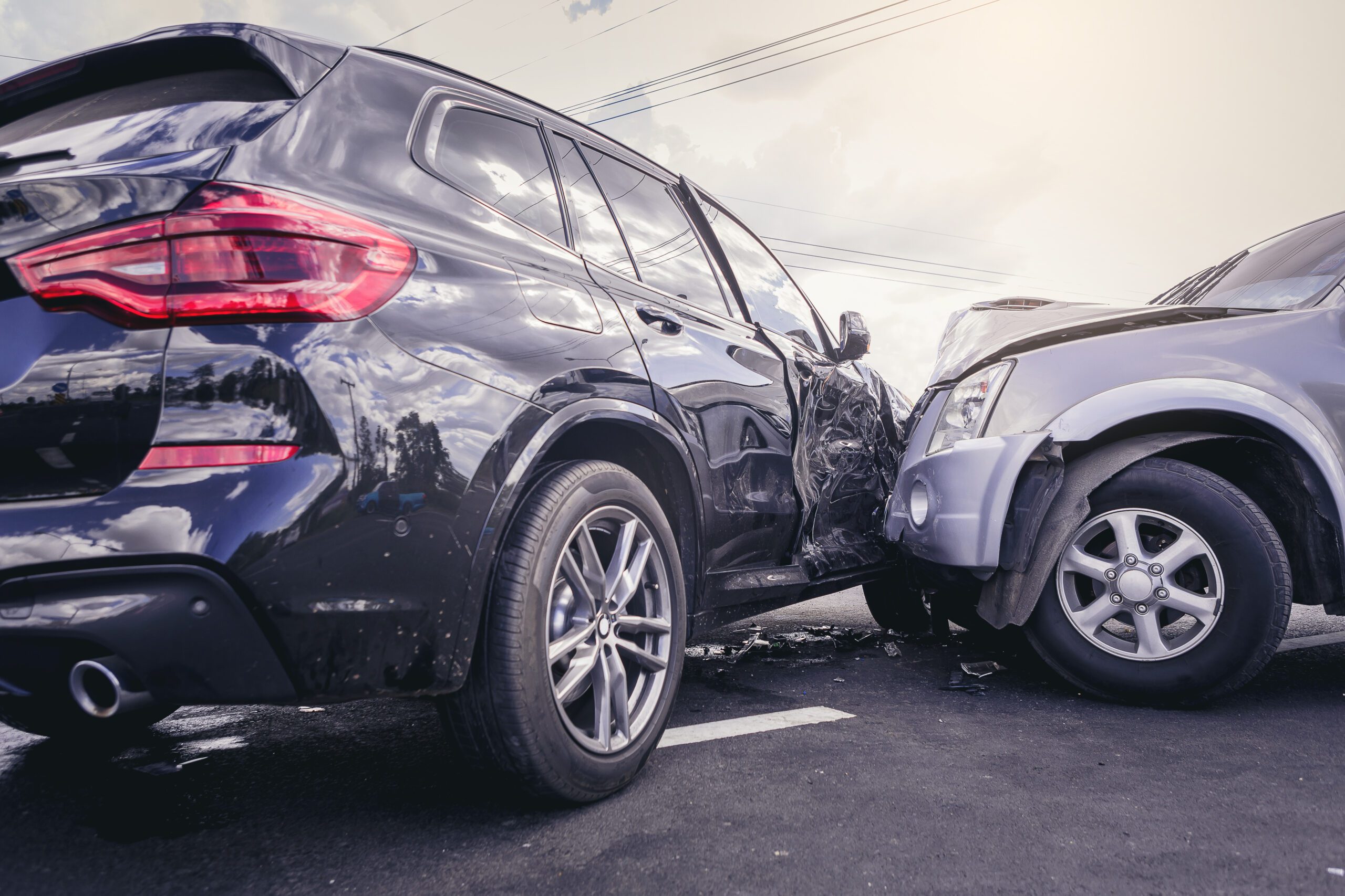An image of a car accident between a black SUV and a gray car.