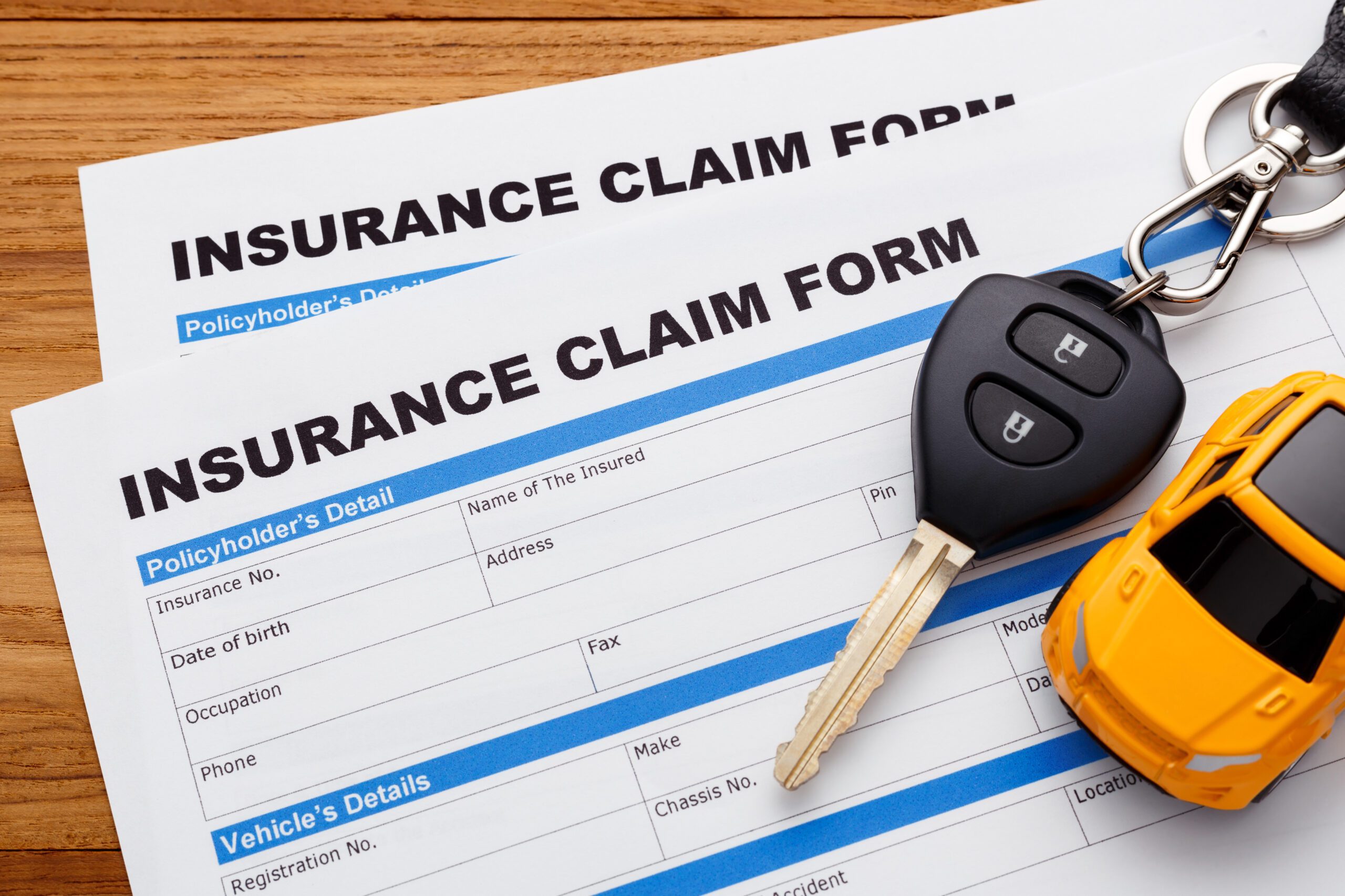 An image of two insurance claim forms with car keys on top of the forms, implying it’s car insurance claim forms.