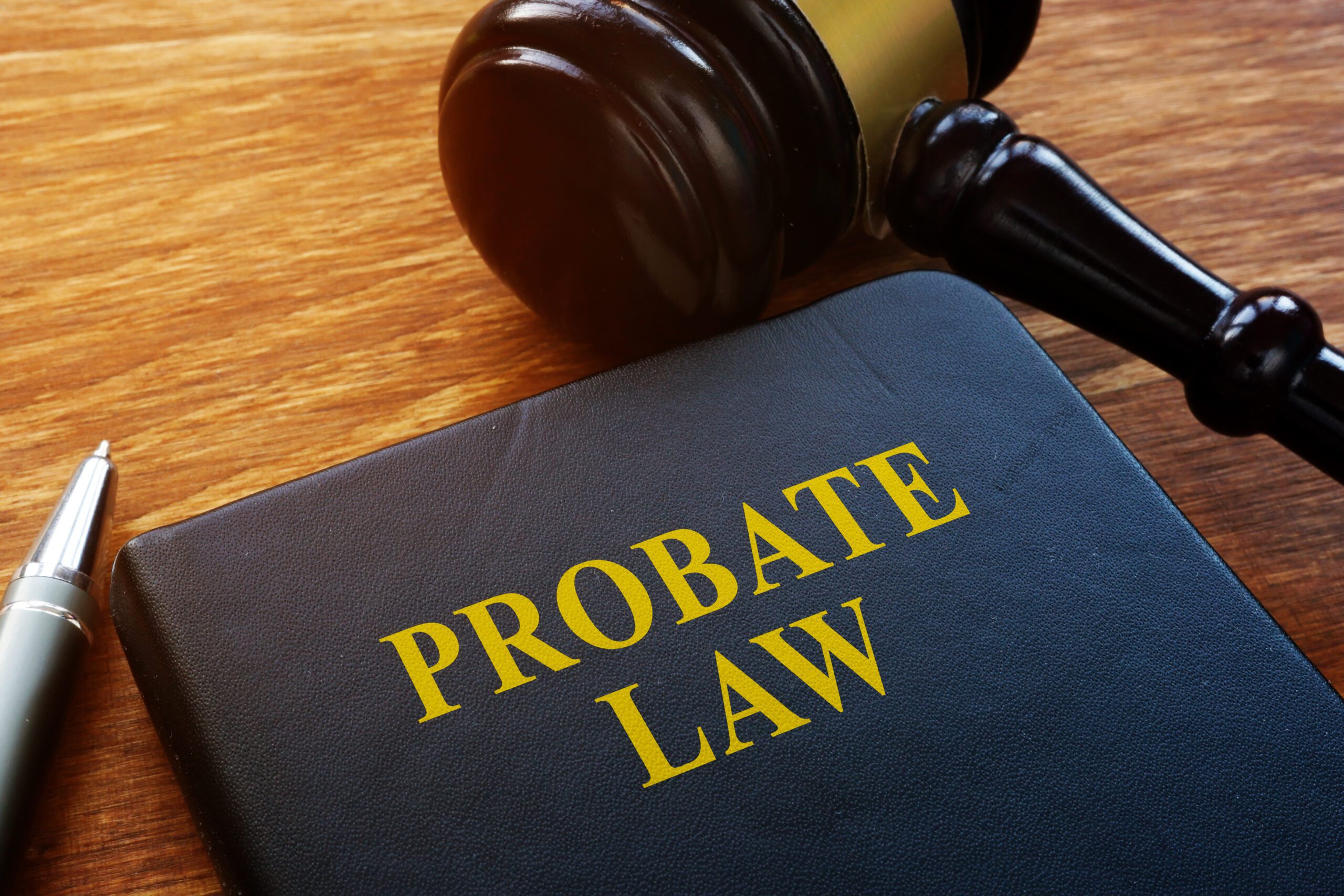 a navy blue book with the words “probate law” written on it in yellow, with a pen and a gavel on either side of the book