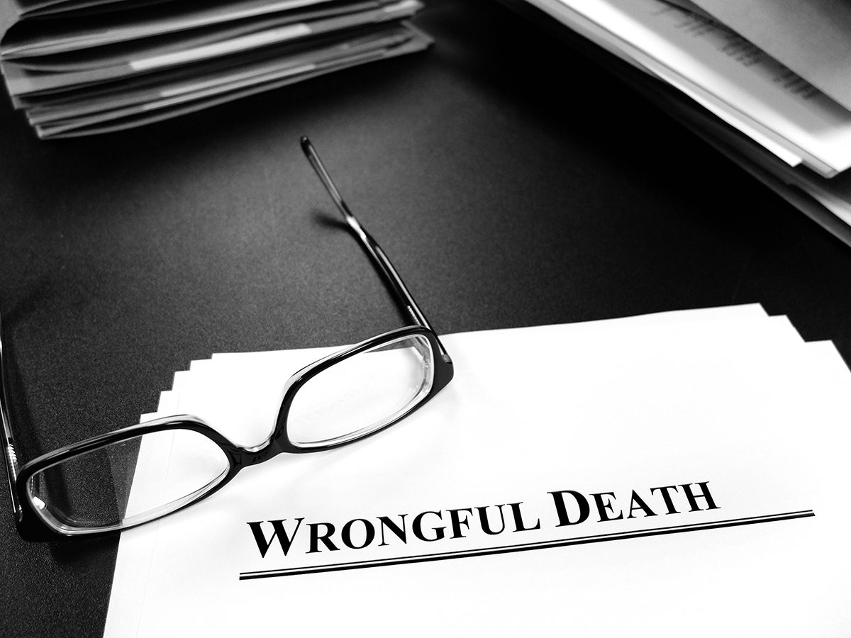 An image of black eyeglasses on top of a stack of papers that says “wrongful death.”
