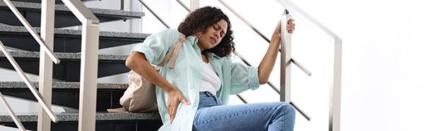 A woman holds her back after slipping and falling on stairs.